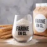 verre doseur rempli de farine à côté d'un paquet de farine ouvert