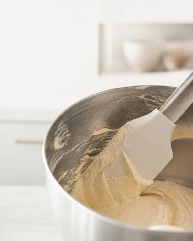 Ustensiles de cuisine maryse en silicone raclant un bol en inox dans une cuisine de pâtisserie